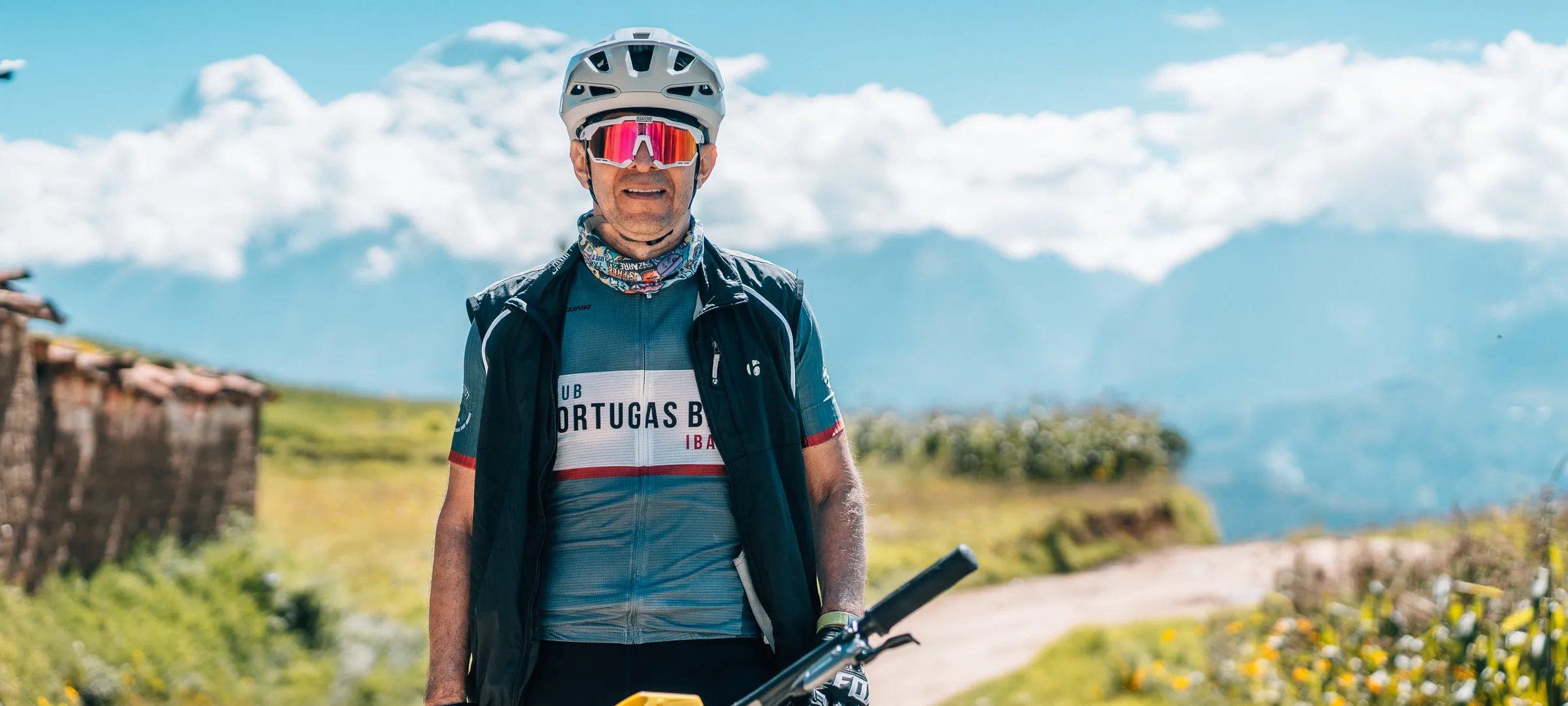 Ciclista en maillot junto a muro de piedra